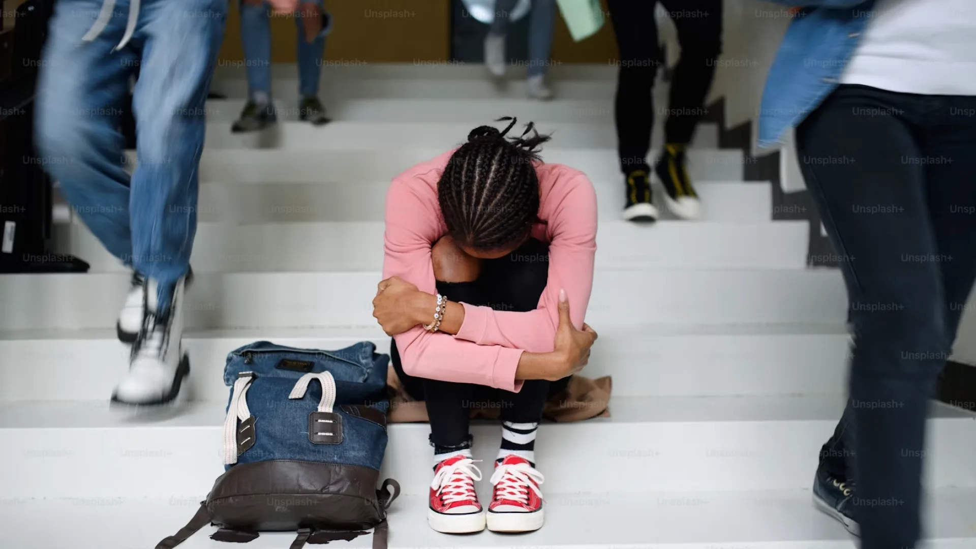 A woman looking upset sitting on the stairs at school