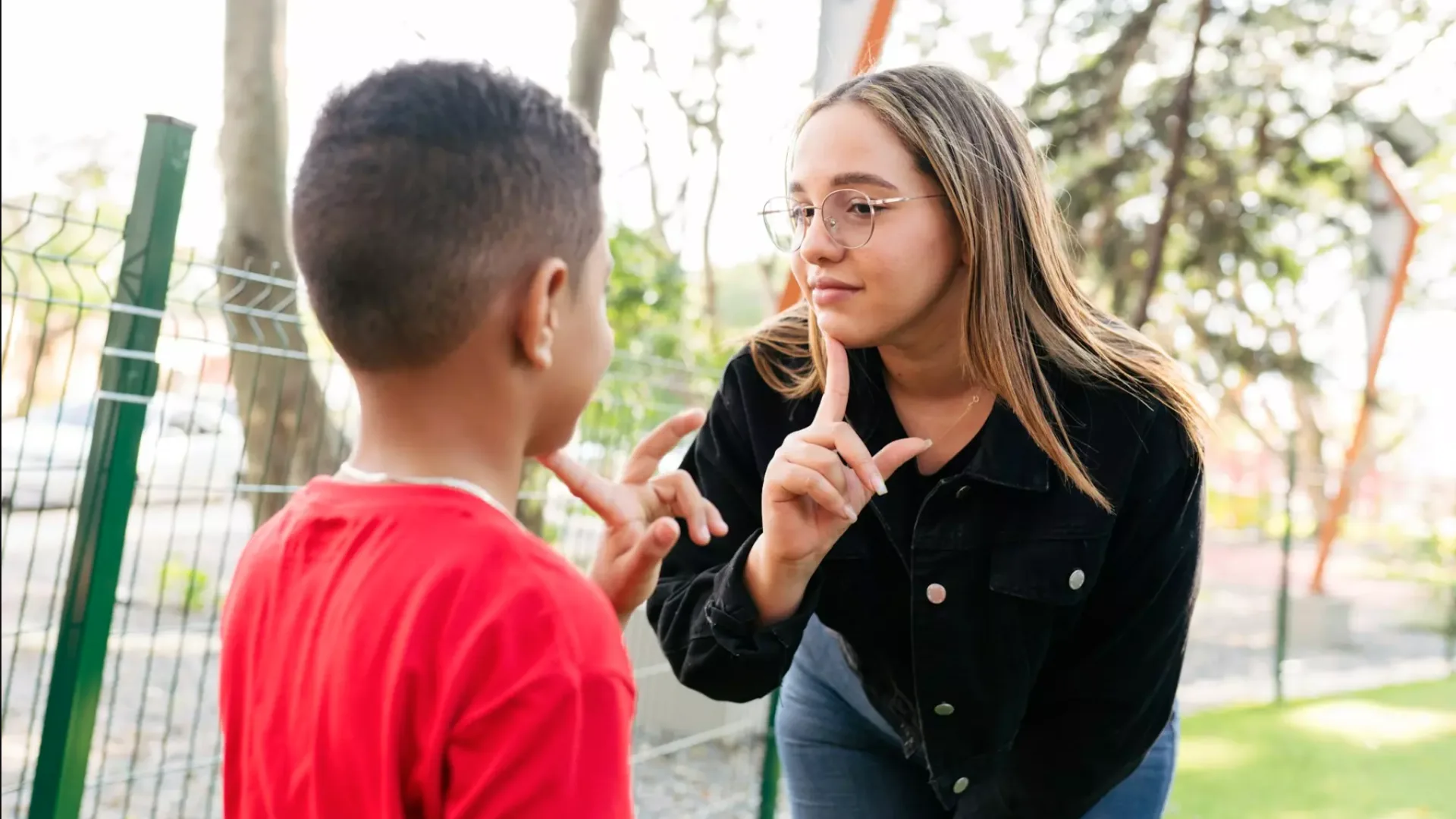 A woman practising sign language with a young boy