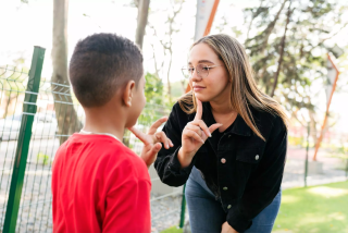 A woman practising sign language with a young boy