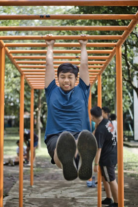 man in blue crew neck t-shirt hanging from monkey bars